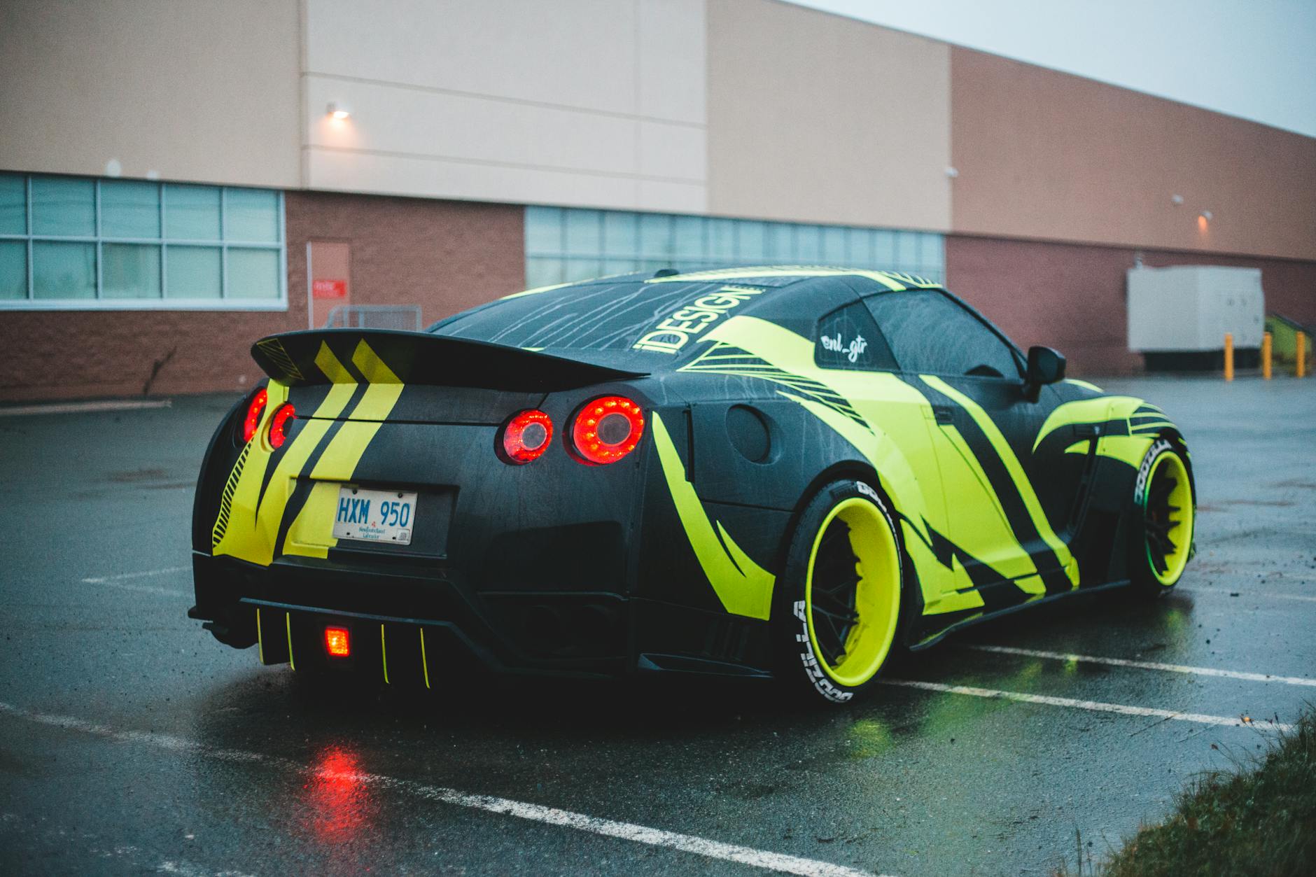 Vibrant custom-designed sports car parked in a wet urban environment showcasing its unique style and color scheme.